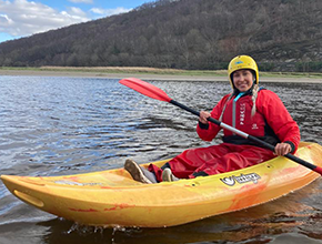 female student kayaking on lake
